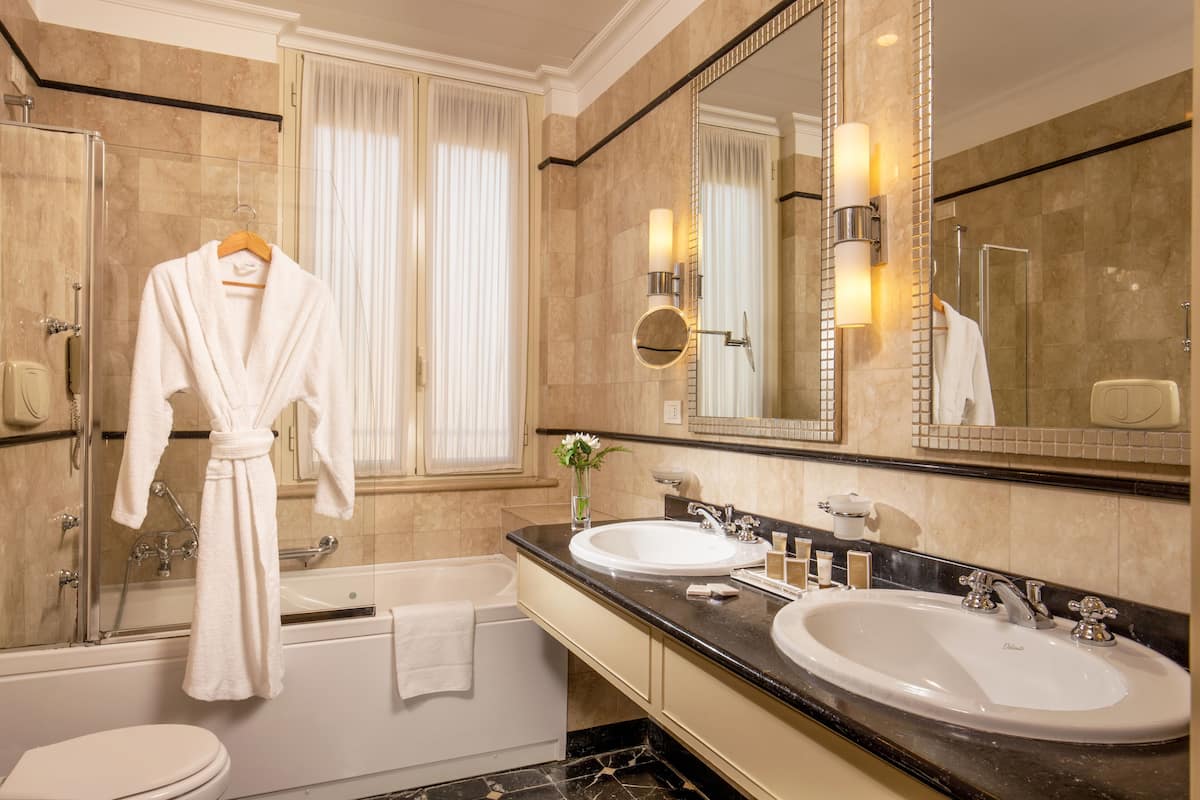 A bathroom with two sinks, a bathtub, and a large mirror.