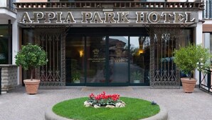 The exterior of the Appia Park Hotel with a large entrance, decorative iron gates, and a landscaped garden area in front. - Appia Park Hotel (Rome)