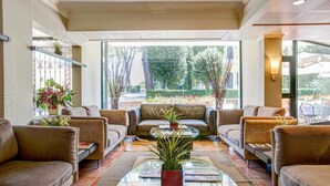 A spacious lobby with leather sofas, a glass coffee table, and potted plants. - Appia Park Hotel (Rome)
