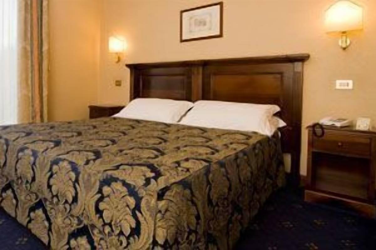 A hotel room with a large bed, two bedside tables, and a nightstand.