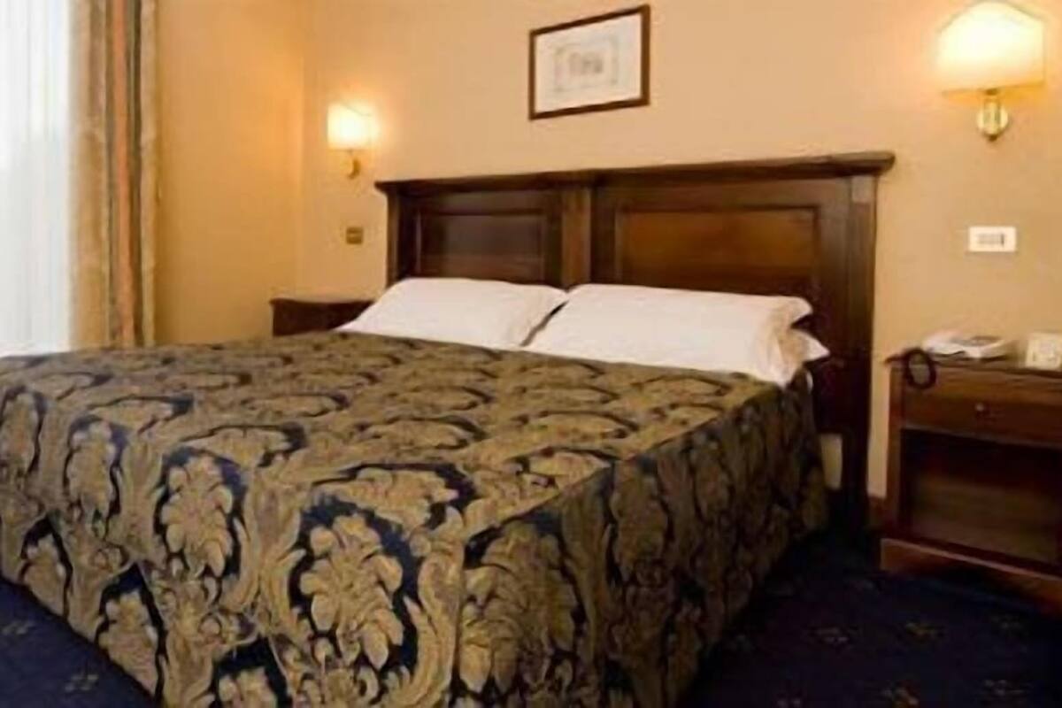 A hotel room with a large bed, two bedside tables, and a nightstand.