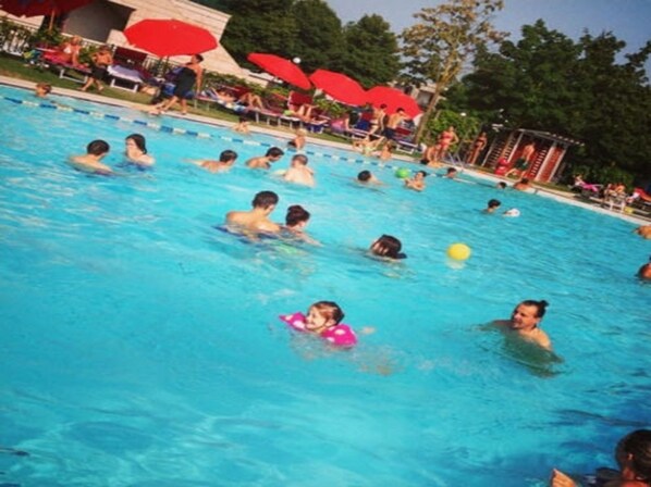 Una piscina al aire libre, sombrillas, tumbonas