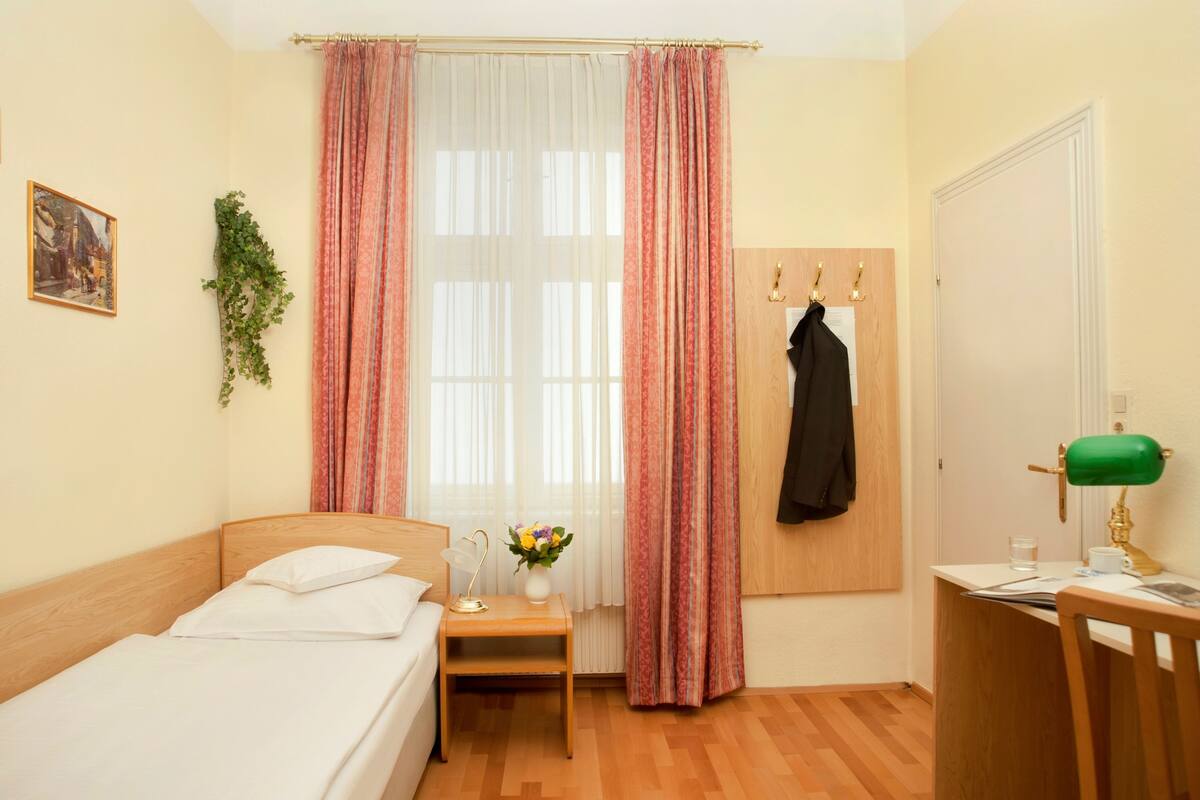 Une chambre bien rangée, avec un lit, une table de chevet, une lampe et un bureau avec une chaise.
