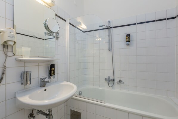 A modern bathroom with a white sink, mirror, and shower.