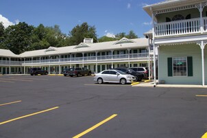 Un motel con varios balcones, un estacionamiento y un pequeño edificio con un letrero que dice 'ATM'.