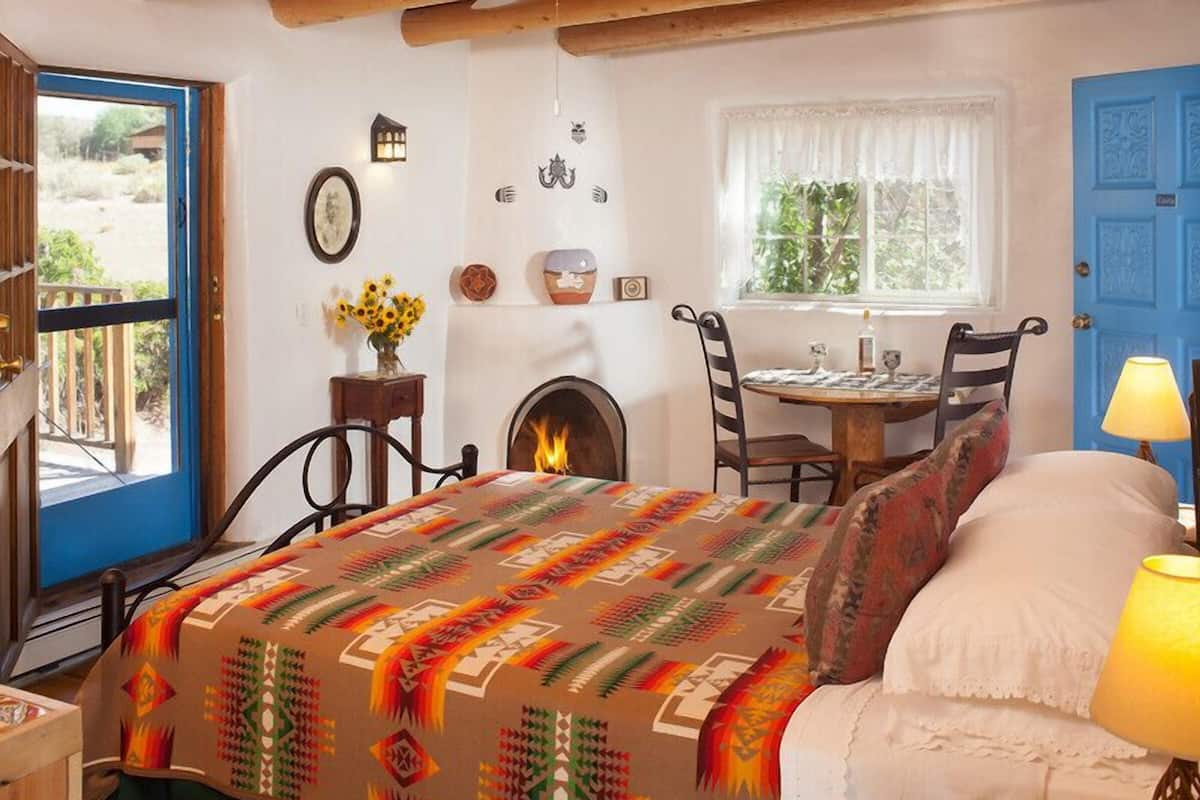 Une chambre confortable avec un lit, une cheminée, une table à manger et une porte bleue.