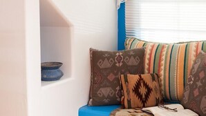 A cozy seating area with a blue sofa, patterned cushions, and a book. - Casa Escondida Bed & Breakfast (Chimayo)