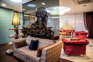 Una habitación con un sofá estampado, un sillón rojo, un adorno de pared y una araña.