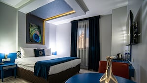 A modern hotel room with a large bed, a desk, and a dining table.