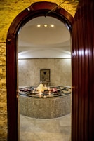 Tinaco circular con velas y toallas, rodeado por un muro de azulejos.