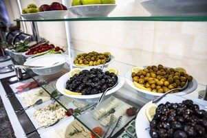 Un bufé con diversos alimentos, como aceitunas, frutas y ensaladas.
