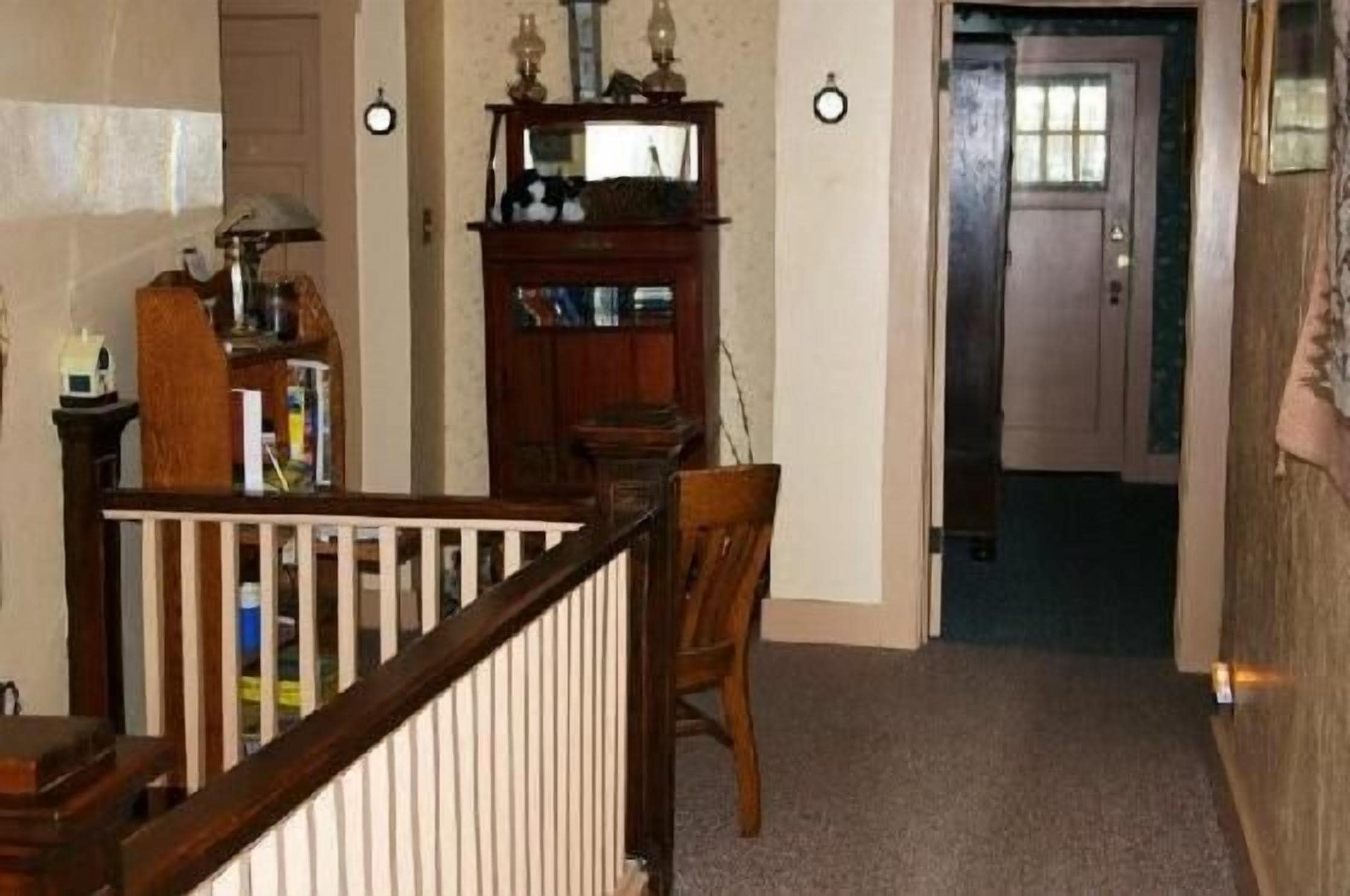 A hallway with a wooden chair, a small table, and a cabinet with shelves.