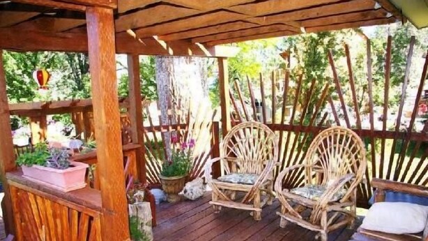 A wooden deck with two wicker chairs and a cushioned bench.