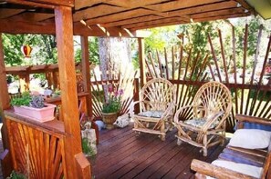 A wooden deck with two wicker chairs and a cushioned bench. - Historic Smith Hotel B&B (Glendale)