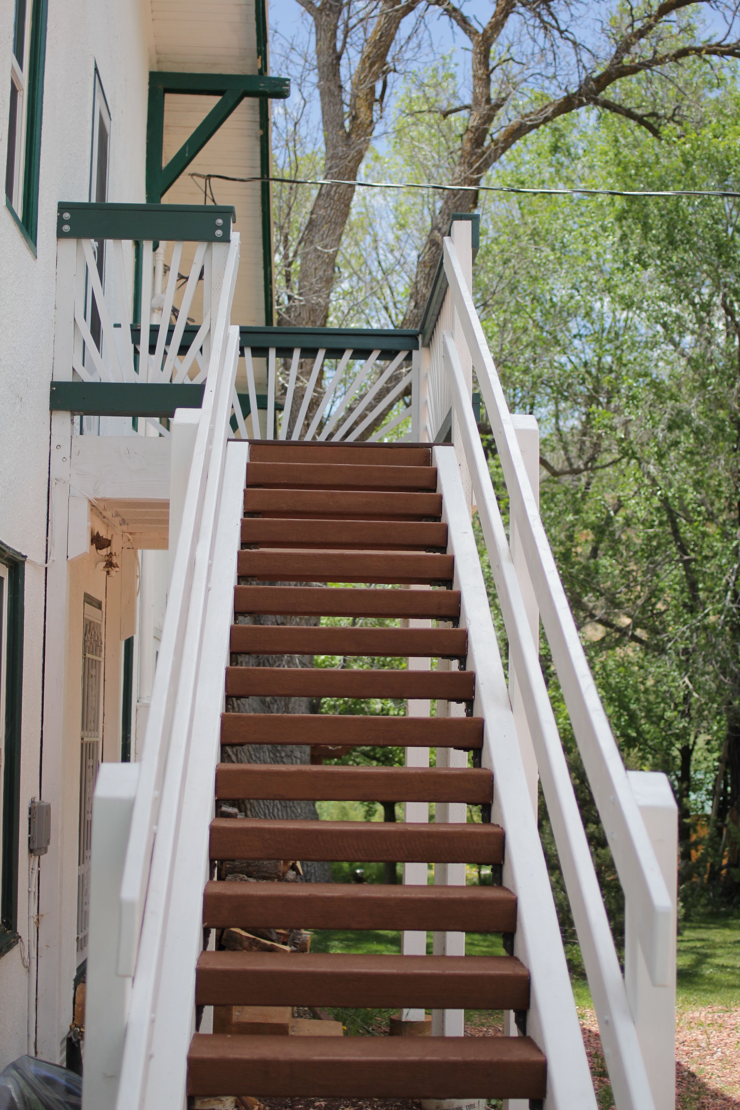 A wooden staircase with white railings leading to a building entrance.