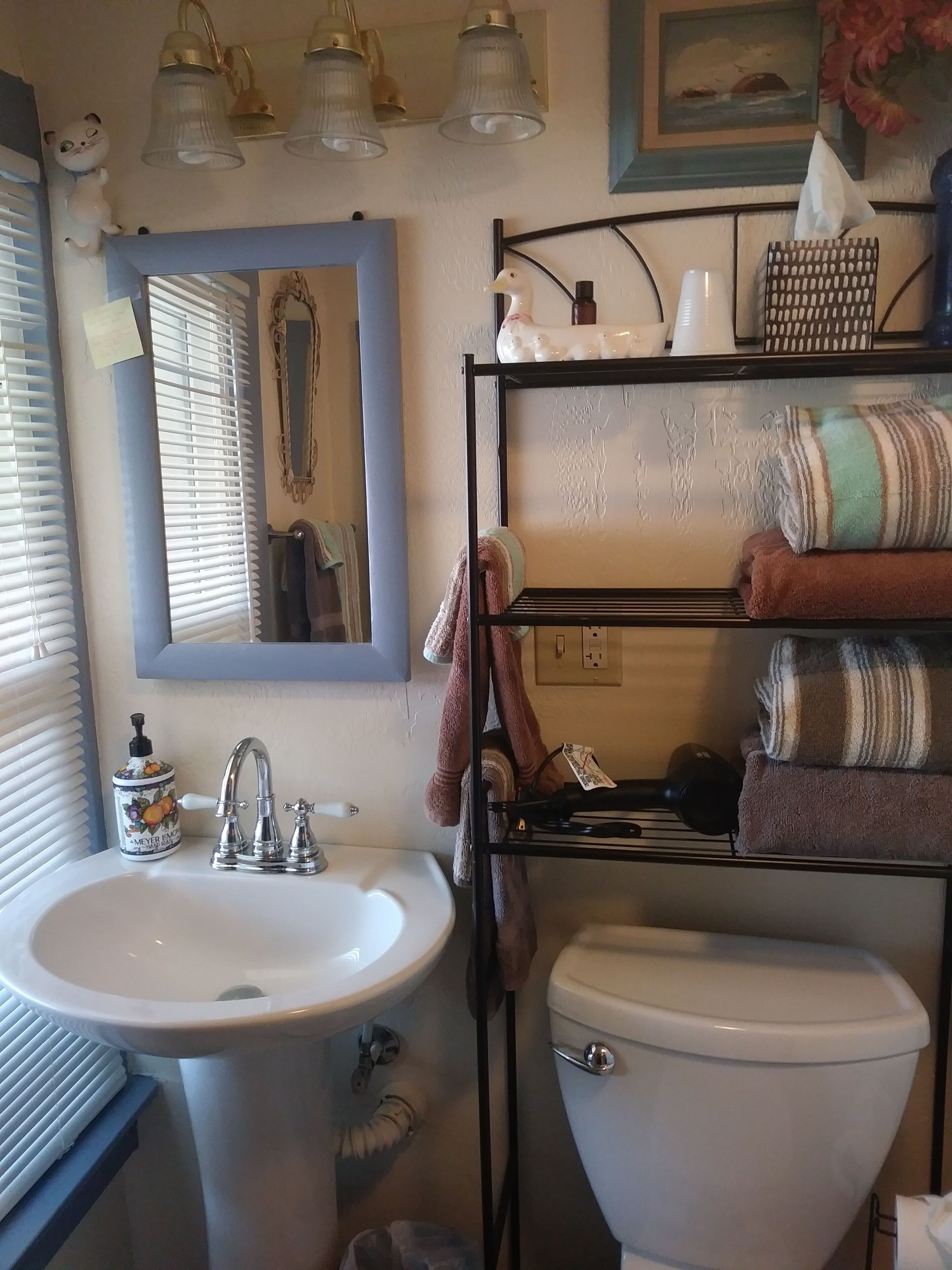 Une salle de bain avec un lavabo, des toilettes et une étagère où sont rangées les serviettes.
