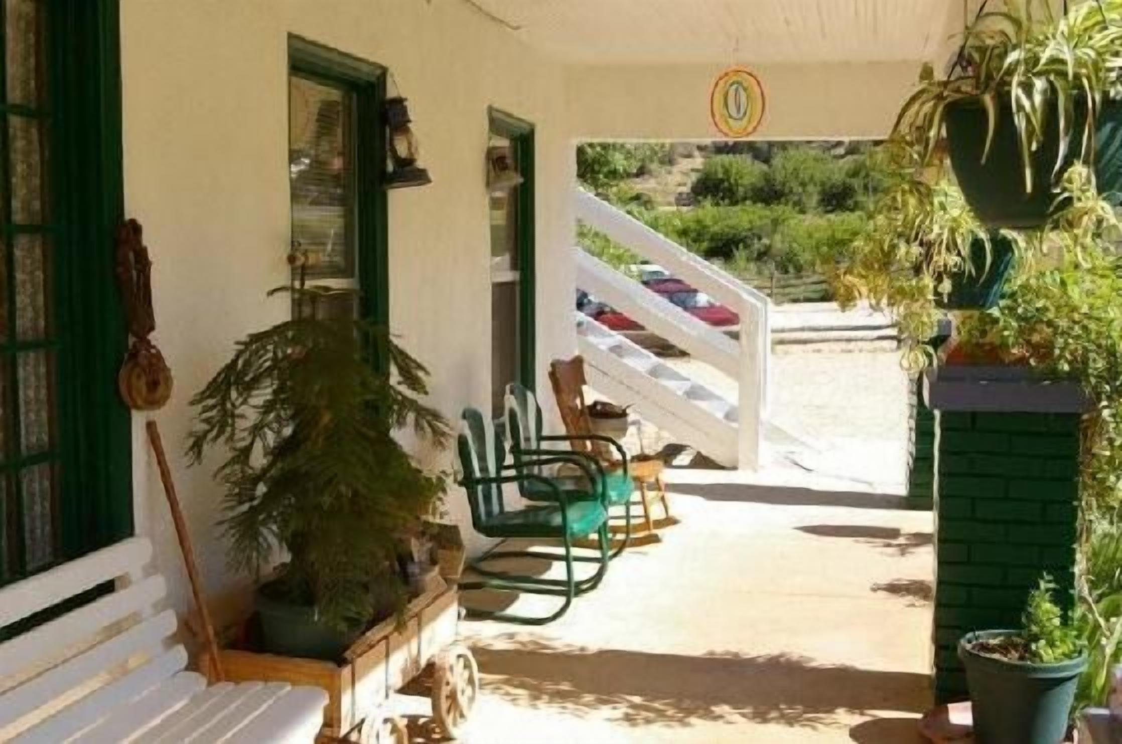 Un área de estar al aire libre con techo, sillas y plantas en macetas.