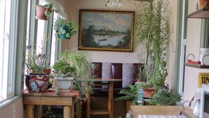 A narrow hallway with wooden benches, potted plants, and a painting on the wall.