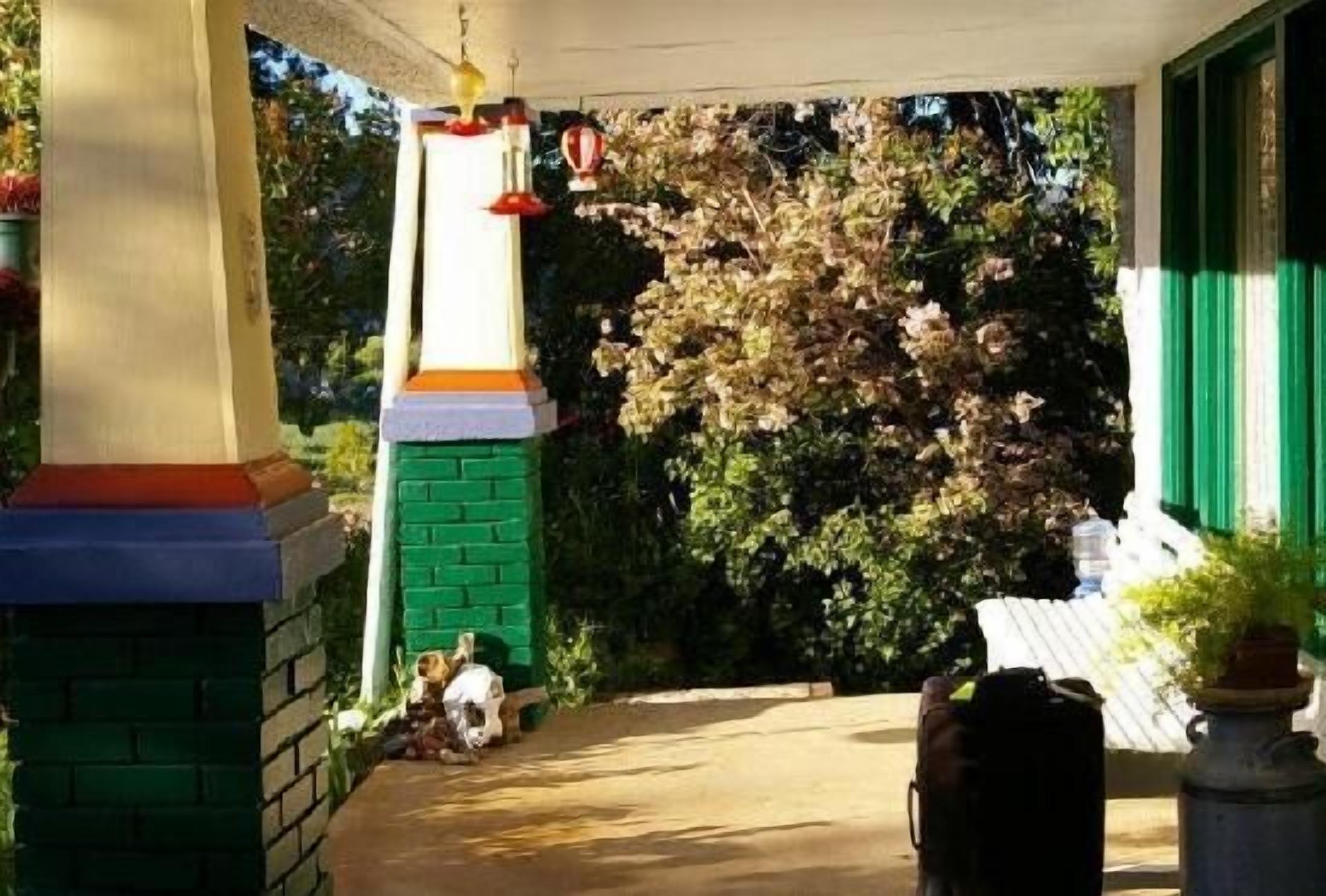 A covered porch with a brick column, a small statue, and a potted plant.