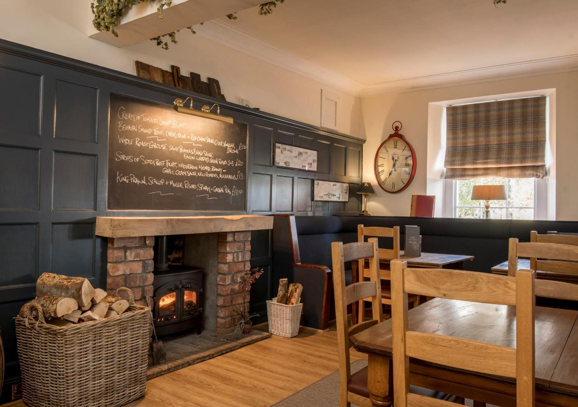 A cozy room with a fireplace, wooden furniture, and a chalkboard menu listing food items.