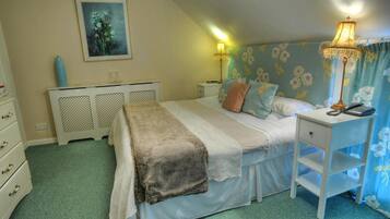 A bedroom with a bed, bedside table, lamp, and a painting on the wall.