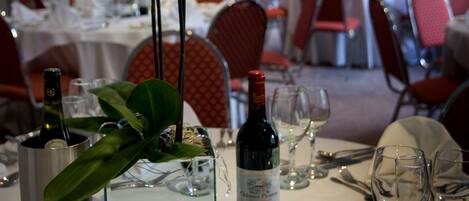 A dining area with tables set for a meal, including wine glasses, plates, and cutlery.
