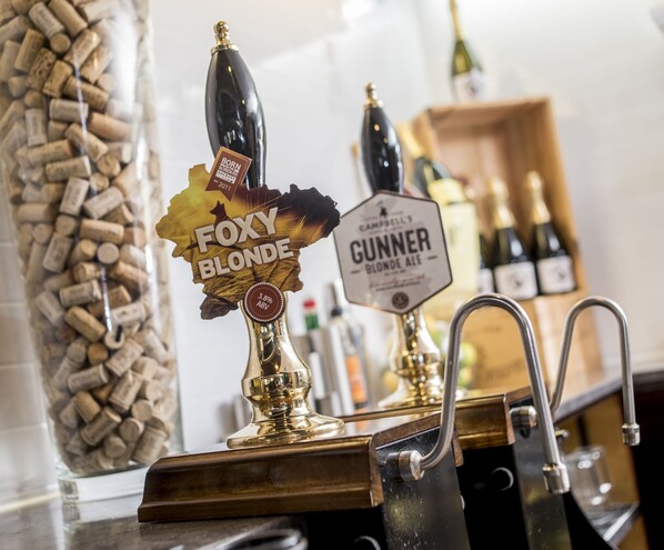 A tap labeled "Foxy Blonde" and "Gunner Blonde Ale" with a background of wine corks.