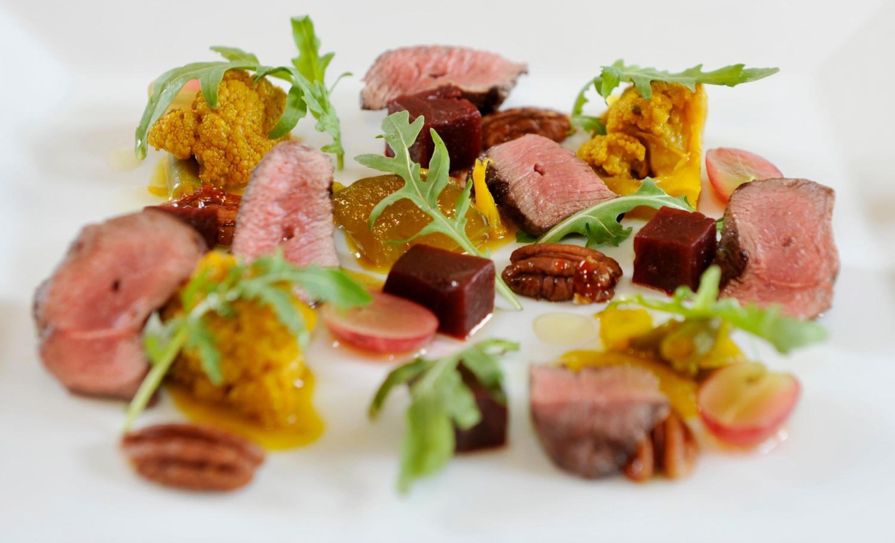 A dish with various food items including meat, vegetables, and nuts.