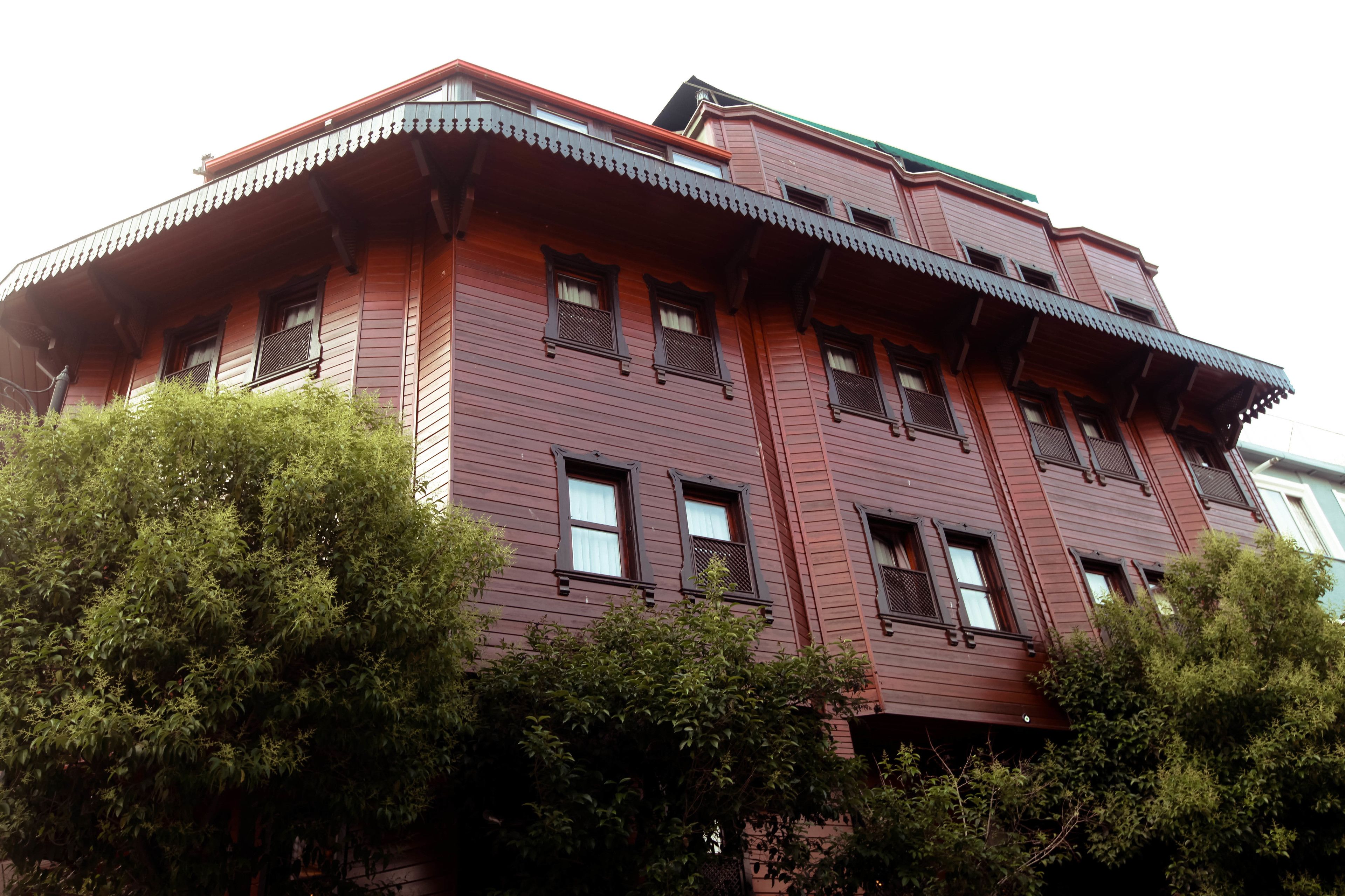 A multi-story building with a red facade, multiple windows, and a green roof.