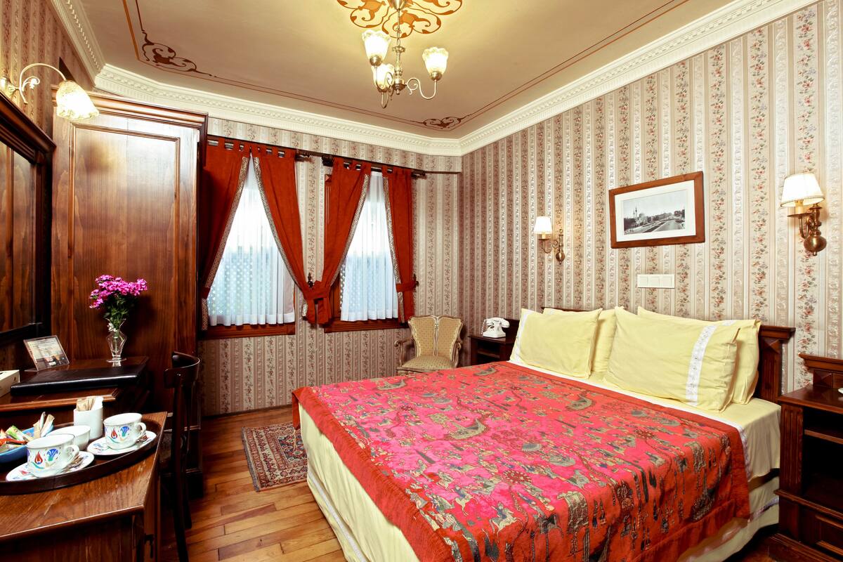 A hotel room with a large bed, wooden furniture, a desk with a telephone, and a picture on the wall.