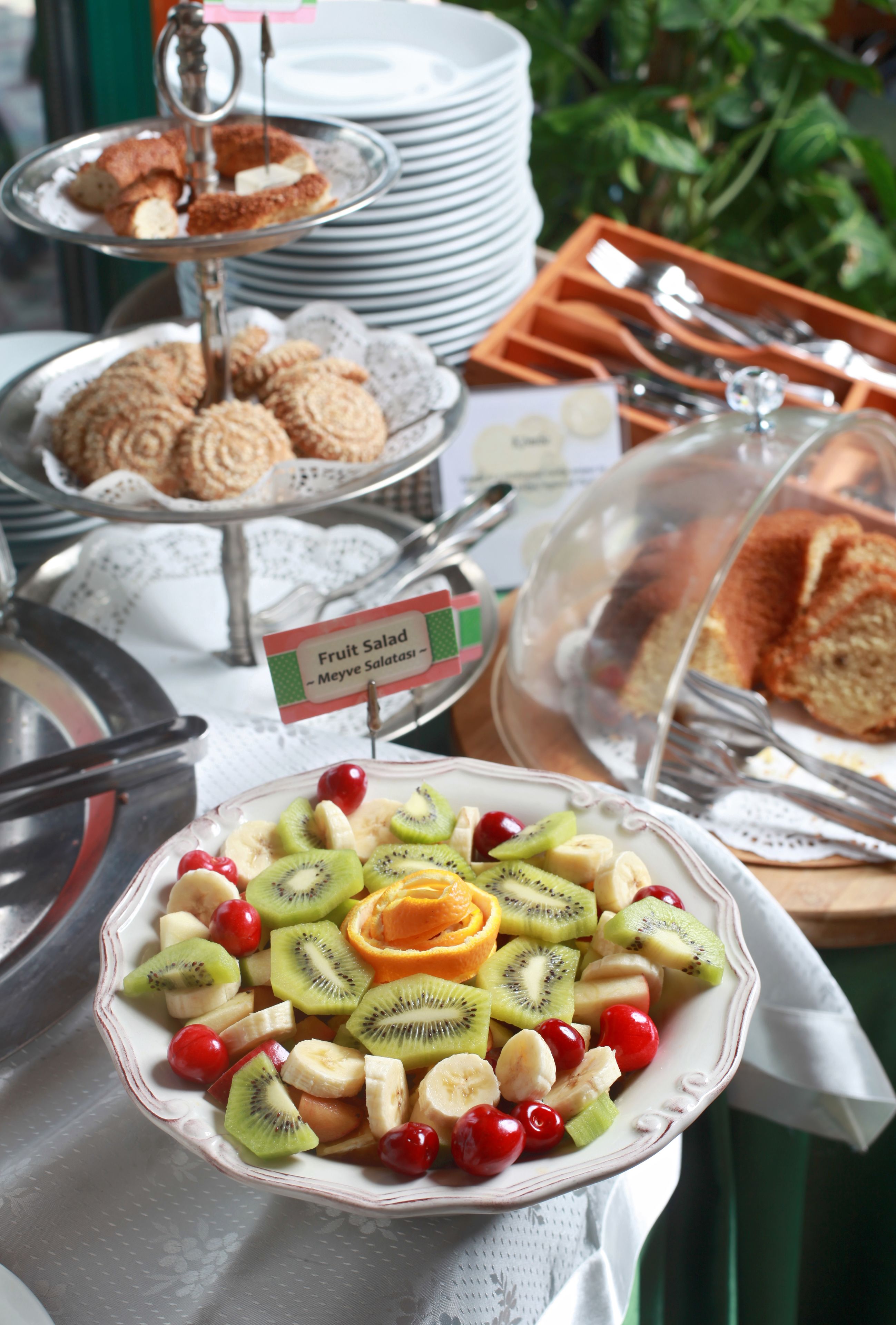 A buffet with various food items including fruit salad, pastries, and bread.
