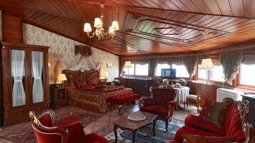 Una habitación tradicional con una cama grande, muebles tapizados en rojo, una araña y un techo de madera.