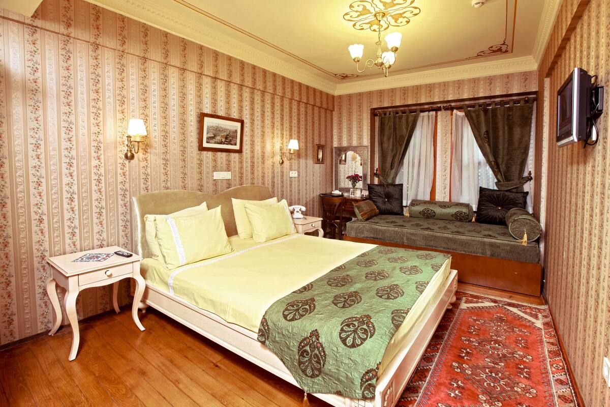 A bedroom with a bed, bedside tables, a nightstand, a mirror, and a television.