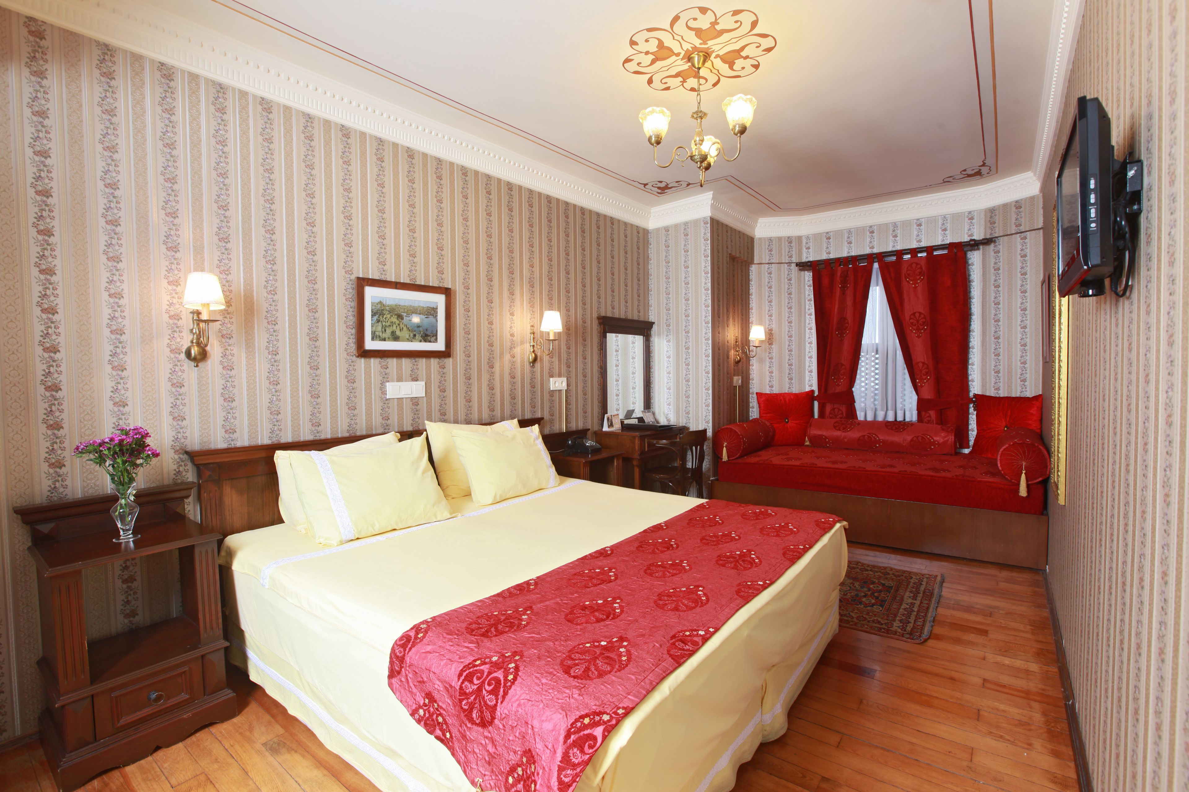 Habitació d'hotel amb un llit gran, un escriptori, una televisió i un sofà vermell.