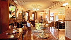 A spacious lobby with a wooden reception desk, a large ornate chandelier, and a seating area with vintage chairs. - Dersaadet Hotel - Special Class (Istanbul)