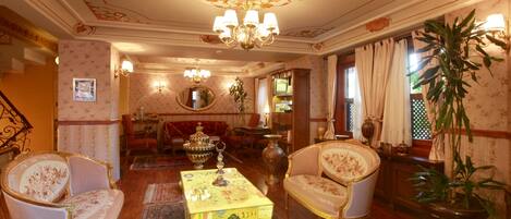 A traditional room with ornate furniture, a chandelier, and a large potted plant.