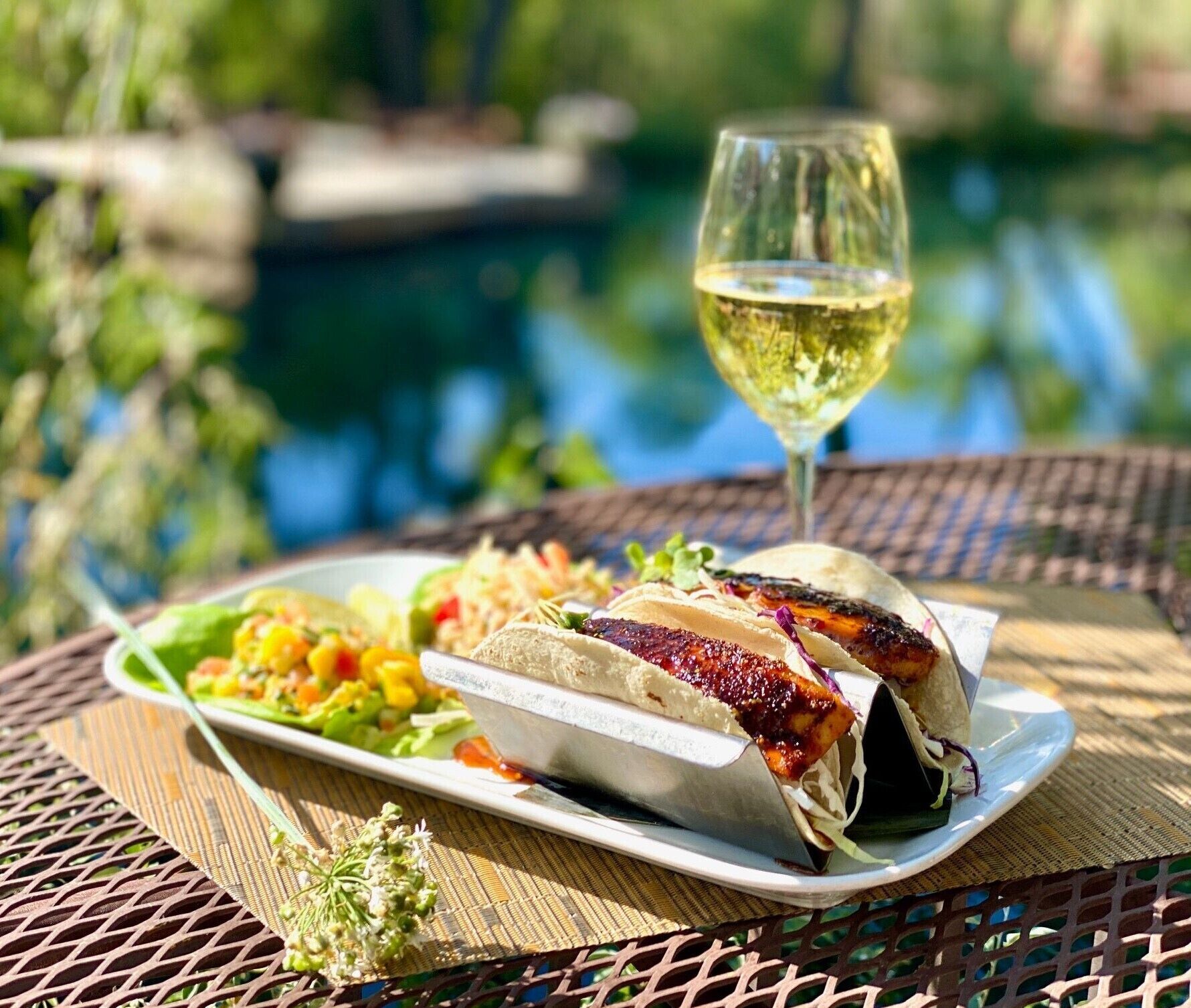 A meal with tacos and a salad on a table by a pool.