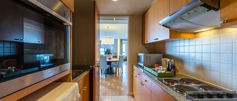 A modern kitchen with stainless steel appliances, wooden cabinets, and a tiled backsplash.
