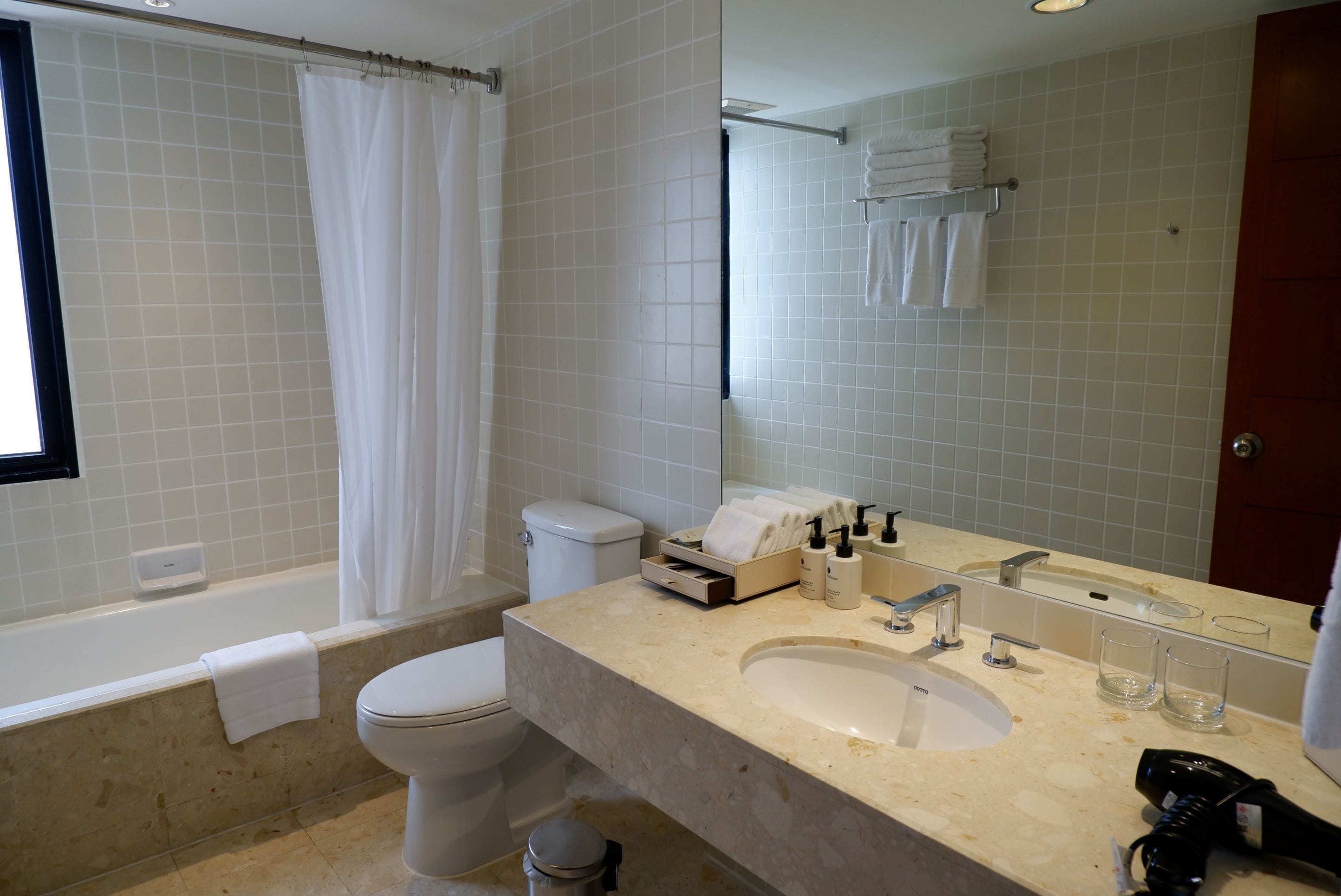 A modern bathroom with a bathtub, toilet, sink, and a mirror.