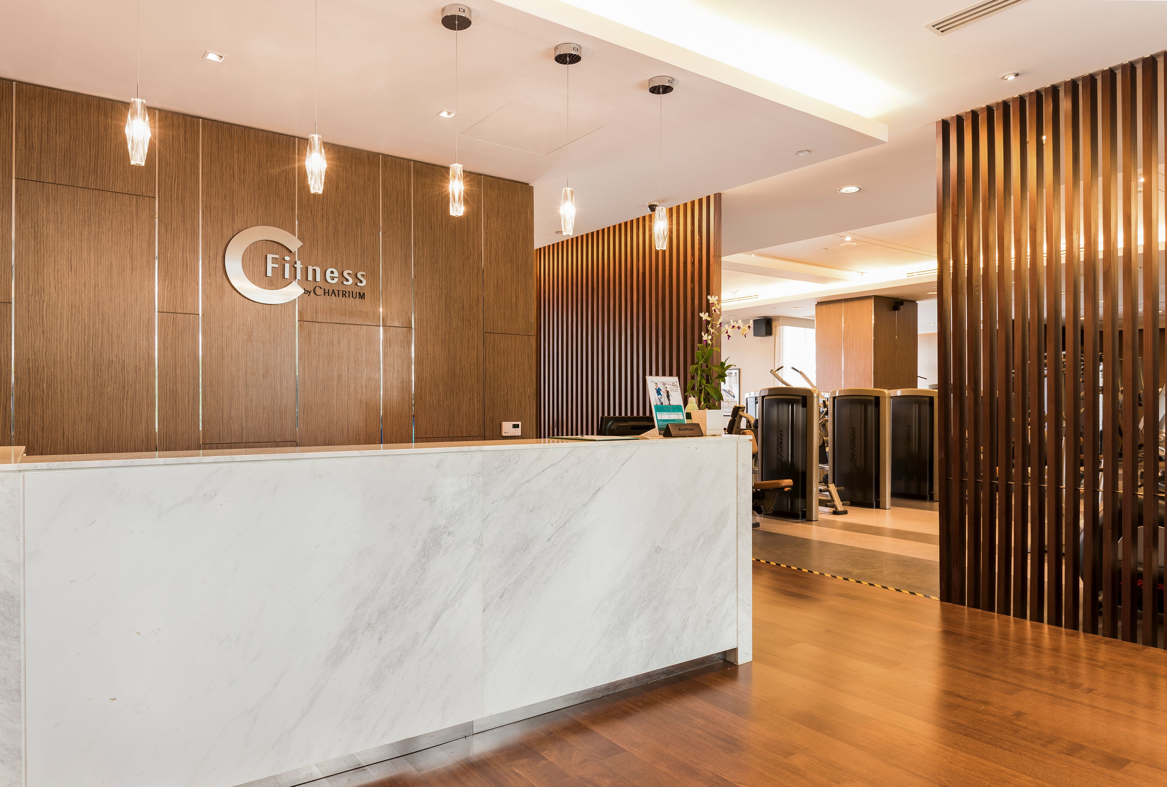 A reception desk with a marble top, wooden paneling, and pendant lighting.