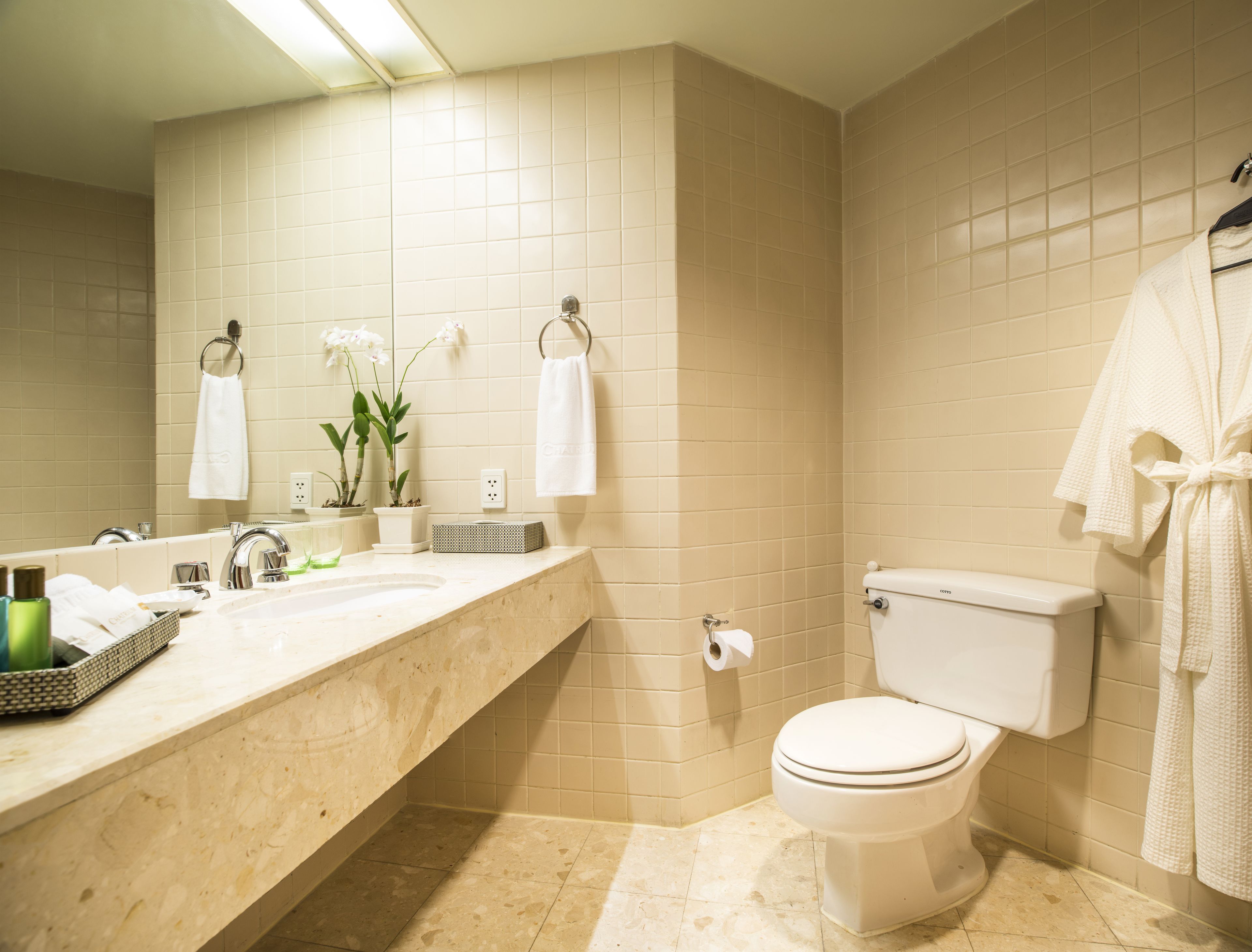 Un baño con lavamanos, inodoro y dos toallas blancas colgadas en la pared.