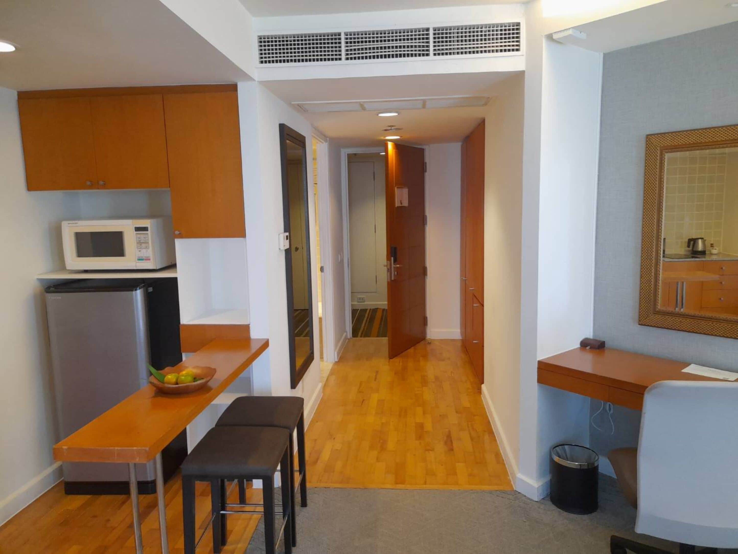 Cocina compacta con microondas, refrigerador y encimera de madera.