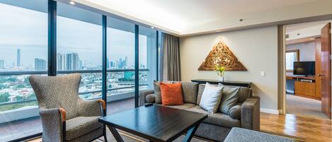 A modern living room with a large window, a sofa, a coffee table, and a decorative wall piece.
