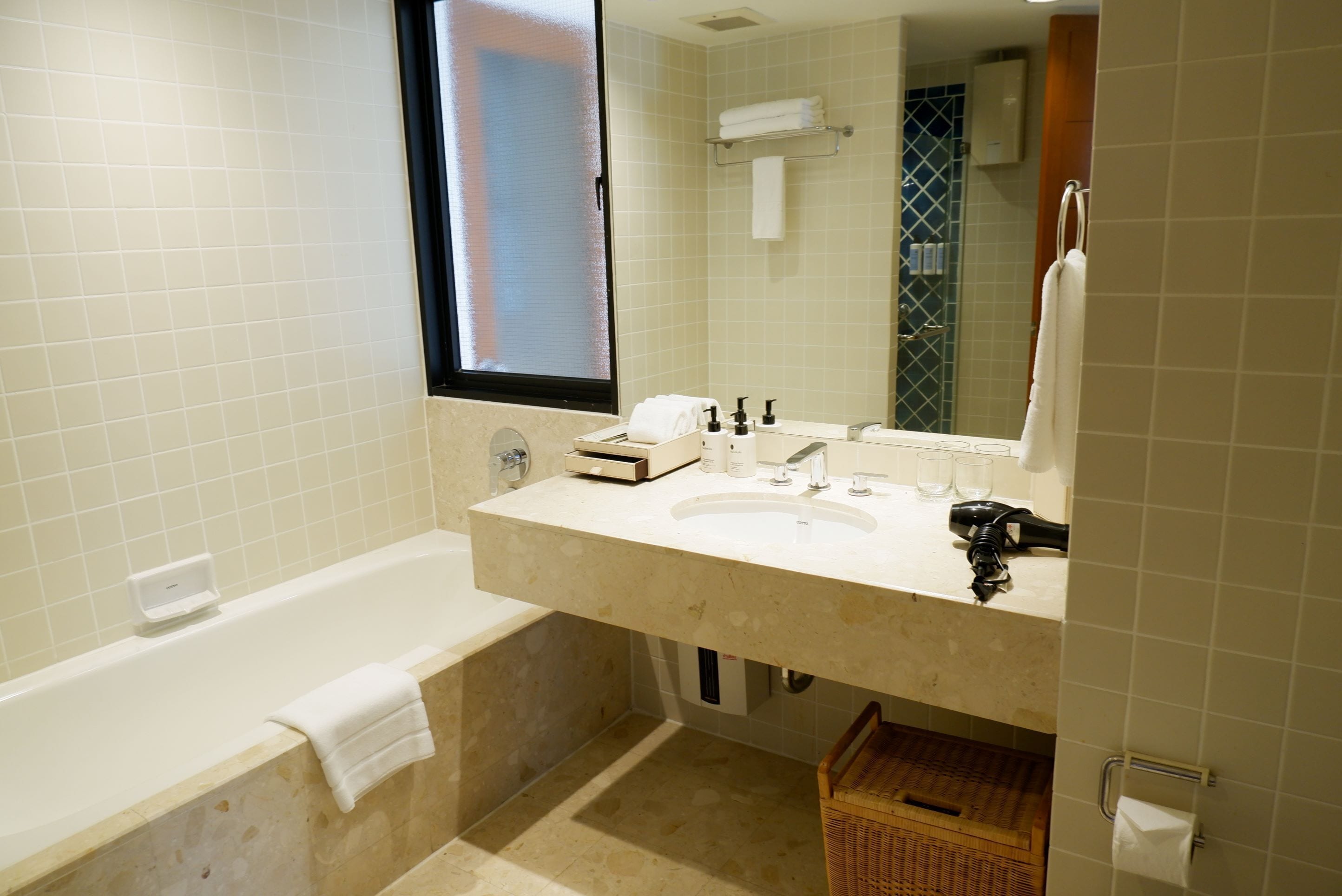 A bathroom with a bathtub, a sink with a mirror, and a window.