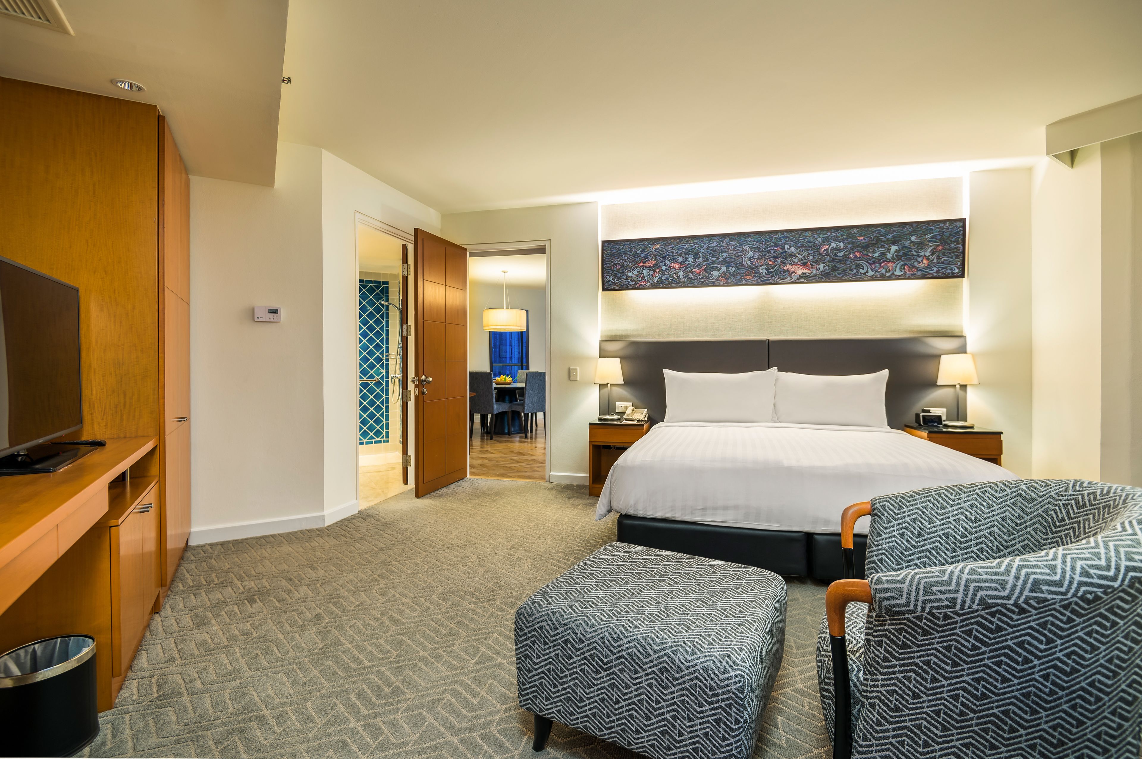 A hotel room with a bed, bedside tables, a desk, a chair, and a television.