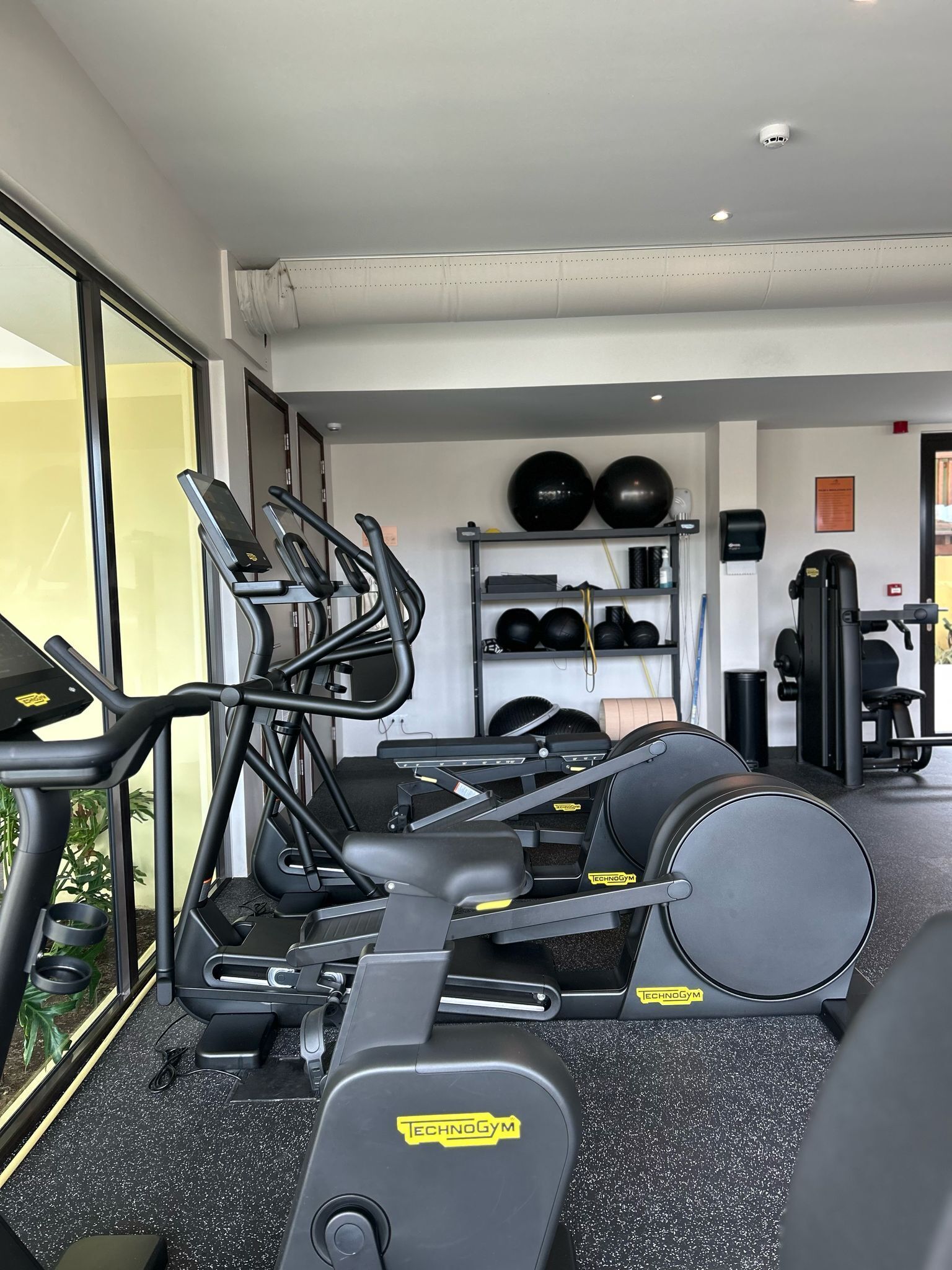 A gym with treadmills, a weight bench, and exercise balls.