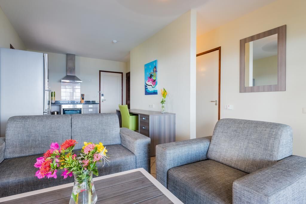 A modern living room with grey sofas, a coffee table, and a painting on the wall.