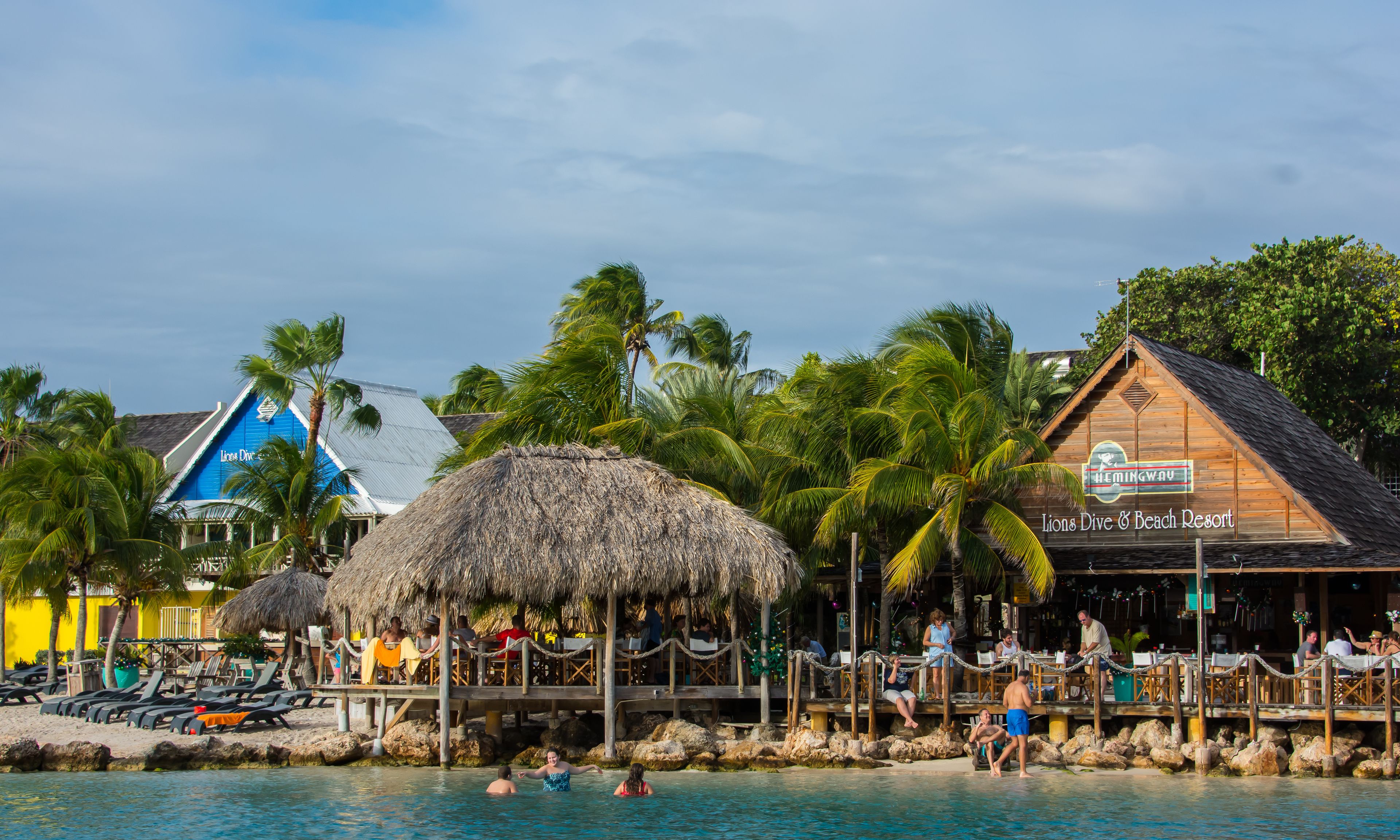 A beach resort with a pool, lounge chairs, and a restaurant.