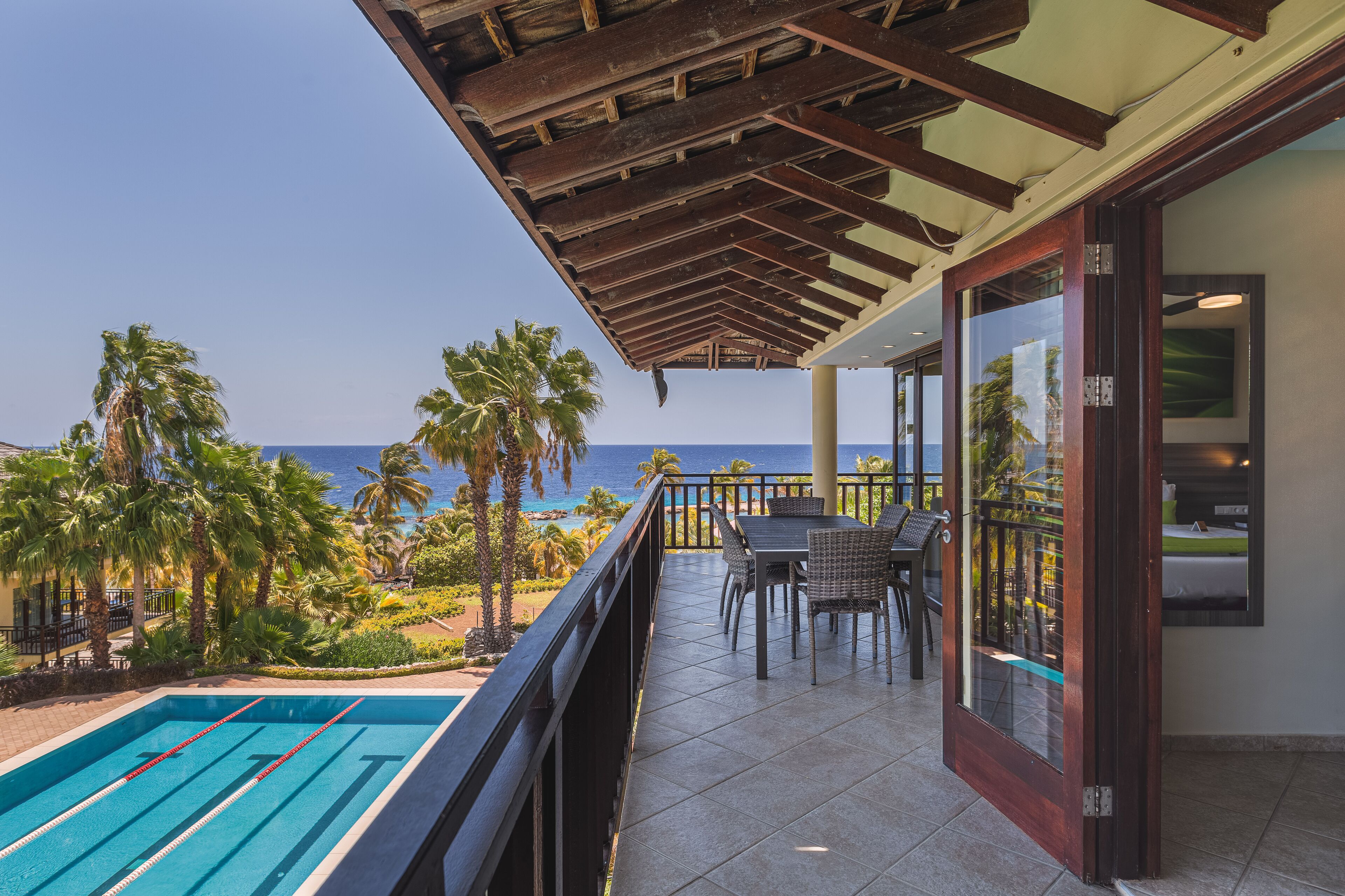 Un balcón con piscina, mobiliario exterior y vista al océano.