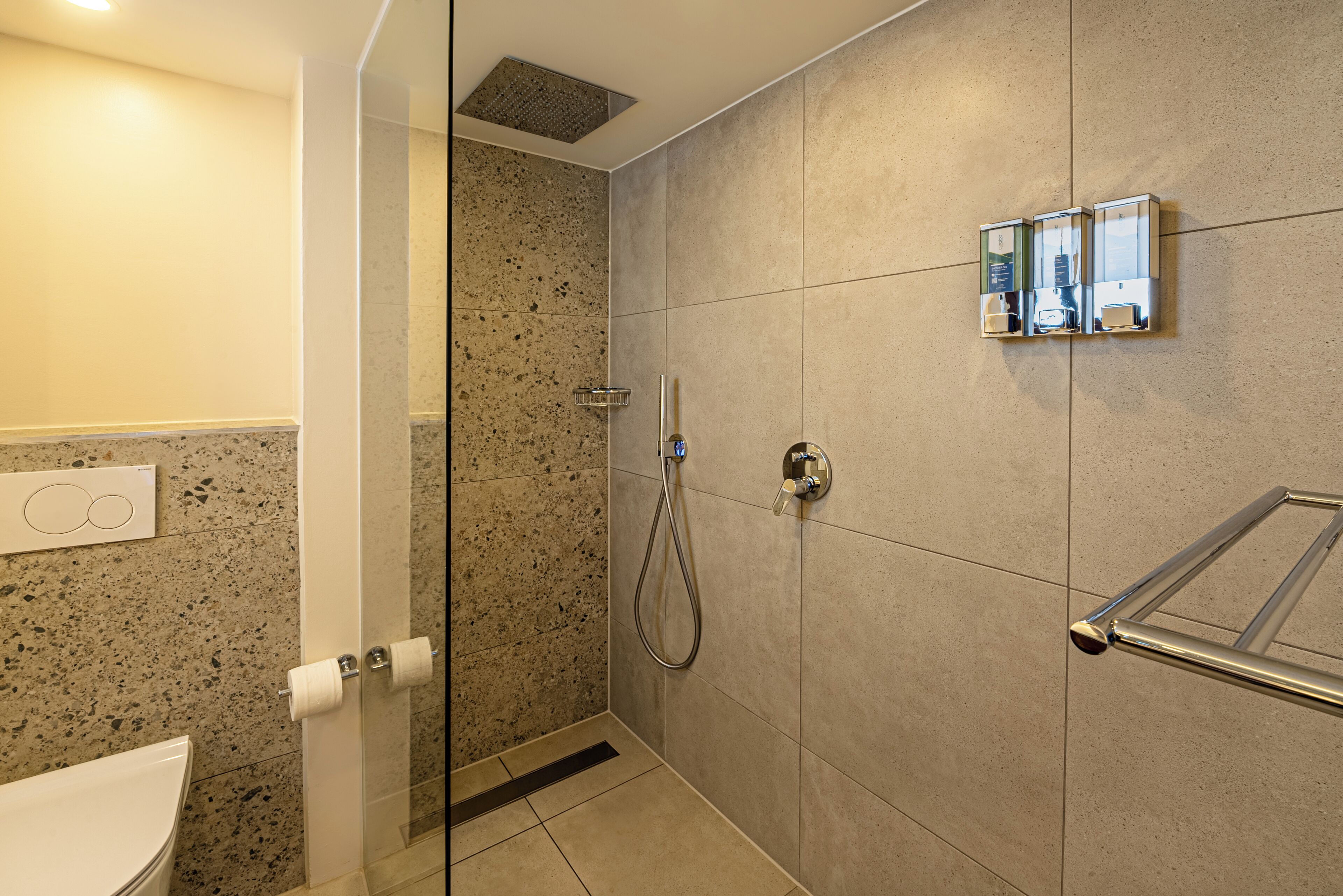 A modern bathroom with a glass shower enclosure, a toilet, and a towel rack.